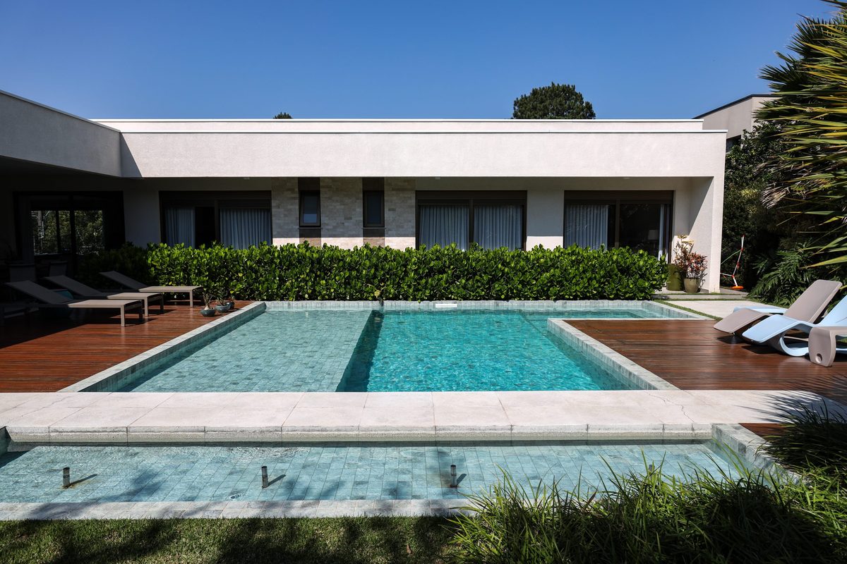 Piscina com deck de madeira integrada a uma residência térrea